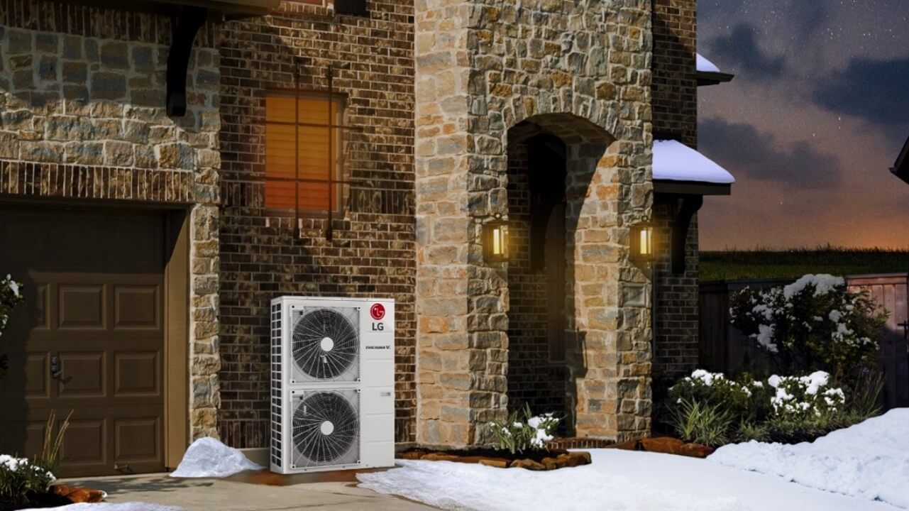 A twin fan LG Therma V air source heat pump installed outside a house with snow on the ground.