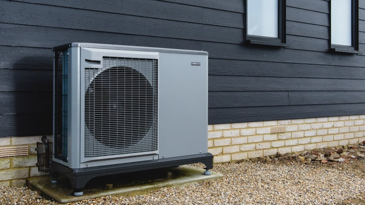 The Nibe F2040 air source heat pump installed outside a house with black cladding.