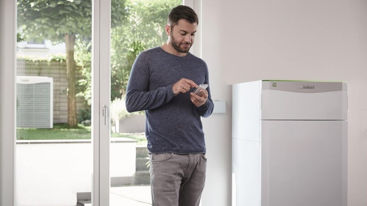 A person controlling the Vaillant flexoTHERM 400V and aroCOLLECT air source heat pump via a mobile app.