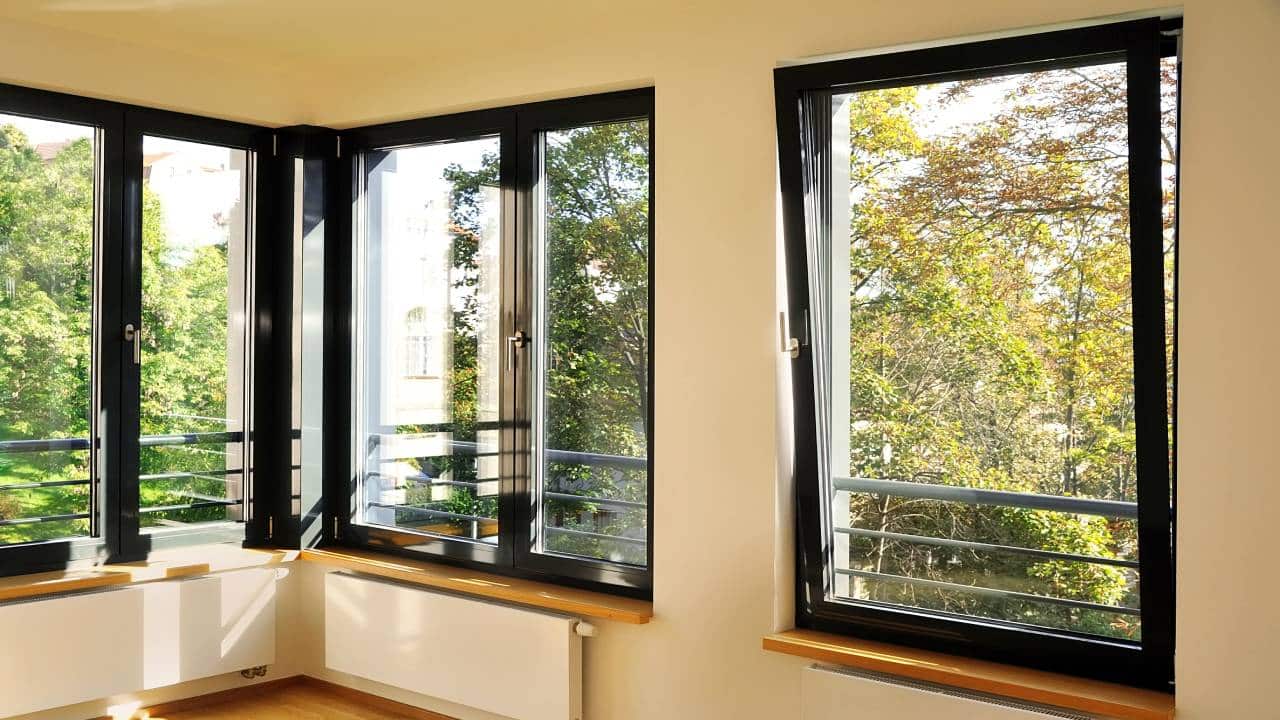 large black aluminium tilt and turn windows above radiators in white room